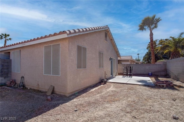 view of side of property with a patio area, a fenced backyard, and stucco siding