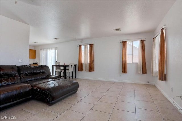 living room with light tile patterned floors, baseboards, visible vents, and a textured ceiling