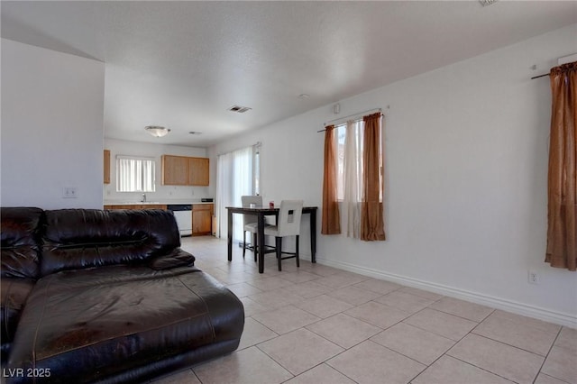 living room with light tile patterned floors, visible vents, and baseboards