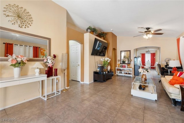 living room featuring arched walkways, ceiling fan, visible vents, vaulted ceiling, and tile patterned floors