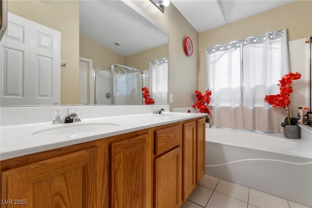 bathroom featuring a stall shower, tile patterned flooring, a garden tub, and a sink