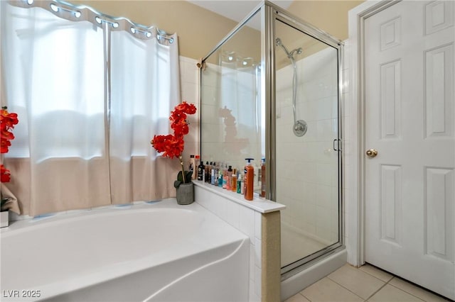 bathroom with tile patterned flooring, a bath, and a shower stall