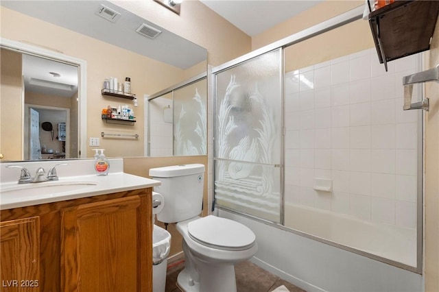 bathroom featuring toilet, bath / shower combo with glass door, vanity, and visible vents