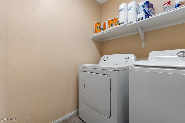 clothes washing area with laundry area, washing machine and clothes dryer, and baseboards