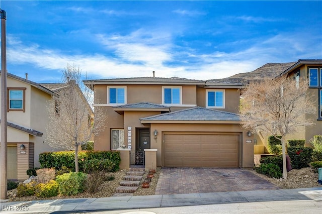 view of front of home with stucco siding, decorative driveway, and a garage