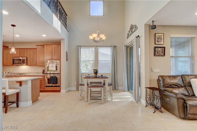 interior space featuring open floor plan, hanging light fixtures, appliances with stainless steel finishes, light stone countertops, and a kitchen bar