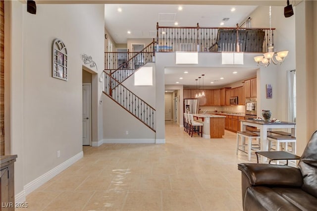 living room with baseboards, a towering ceiling, an inviting chandelier, and stairs