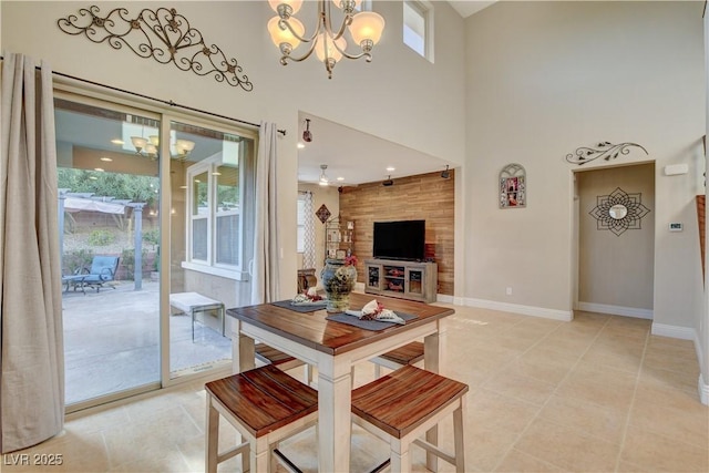 dining area with a towering ceiling, light tile patterned floors, baseboards, and a chandelier