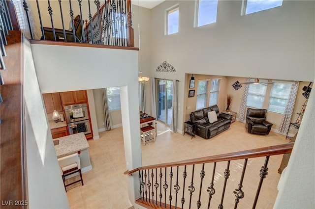 staircase featuring baseboards, a high ceiling, and a chandelier