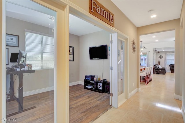 corridor featuring light wood finished floors, a wealth of natural light, and baseboards