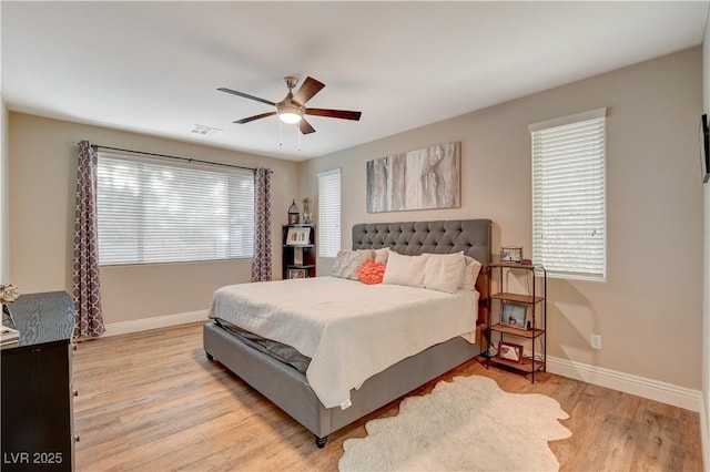 bedroom featuring light wood finished floors, ceiling fan, visible vents, and baseboards