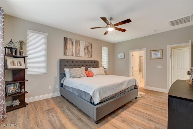 bedroom with ceiling fan, connected bathroom, visible vents, baseboards, and light wood-type flooring