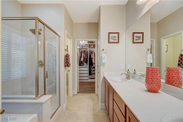 bathroom featuring a shower stall, a walk in closet, tile patterned flooring, and vanity