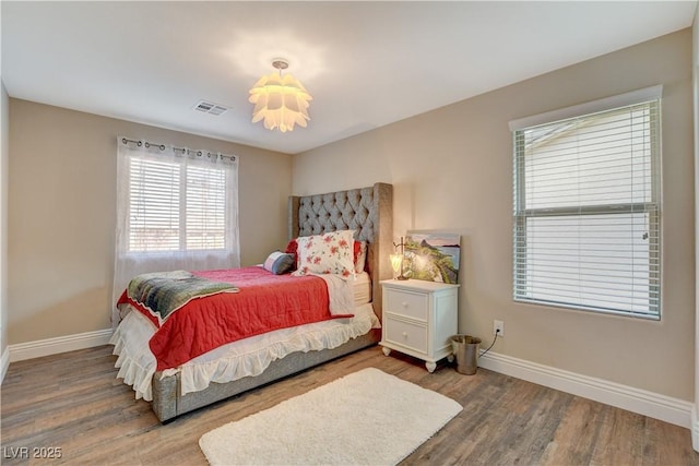 bedroom featuring baseboards, visible vents, and wood finished floors