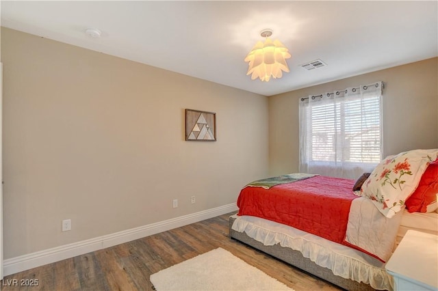 bedroom with baseboards, visible vents, and wood finished floors