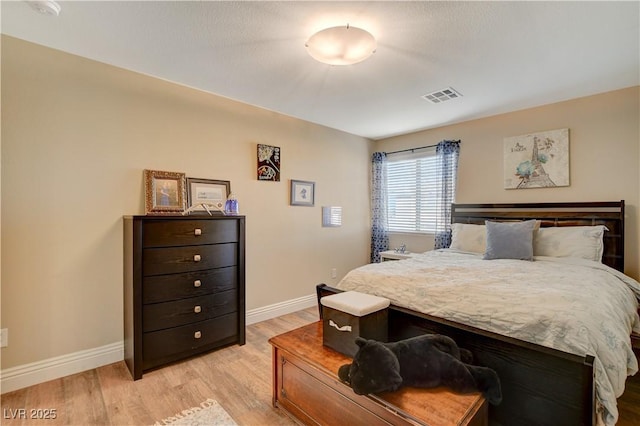 bedroom with visible vents, light wood-style flooring, and baseboards