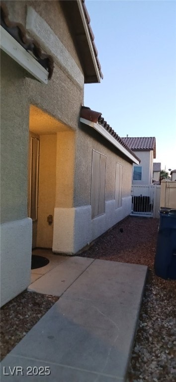 view of side of home with a patio area, fence, and stucco siding