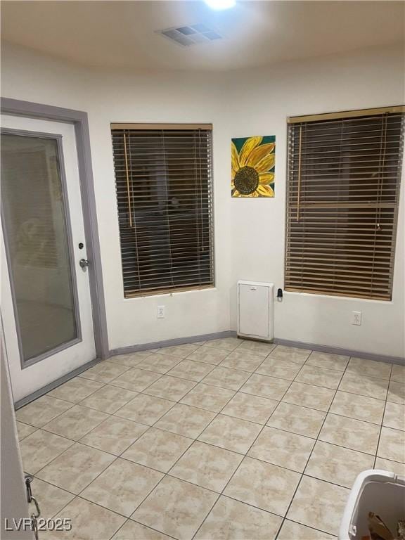 spare room featuring light tile patterned flooring, visible vents, and baseboards