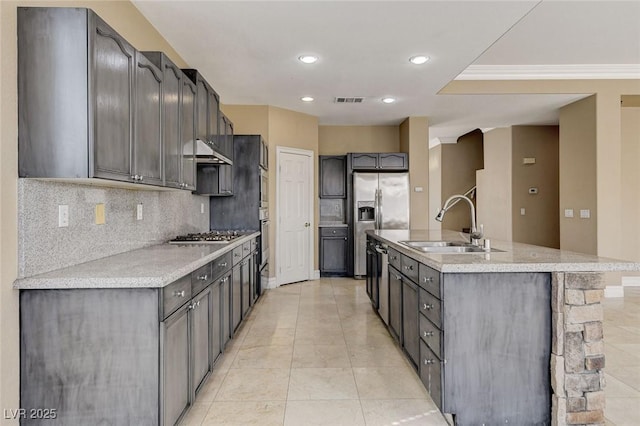 kitchen with an island with sink, under cabinet range hood, light countertops, and a sink