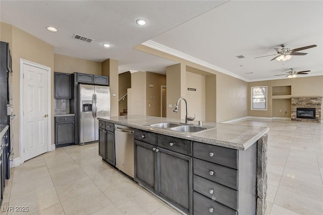 kitchen with a kitchen island with sink, stainless steel appliances, a sink, visible vents, and crown molding
