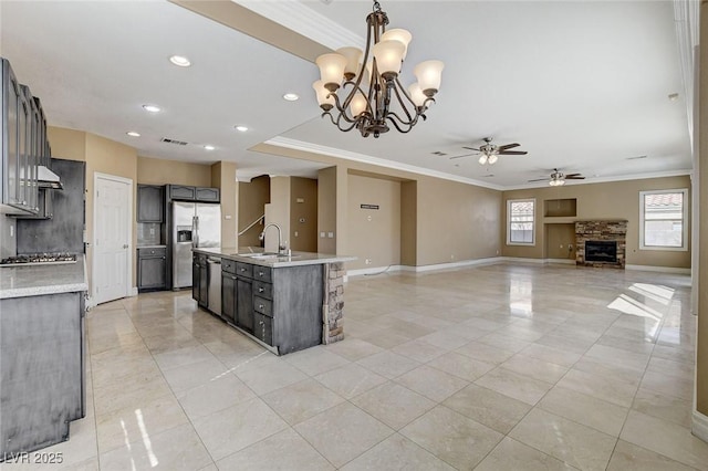 kitchen featuring pendant lighting, stainless steel appliances, open floor plan, a kitchen island with sink, and a sink