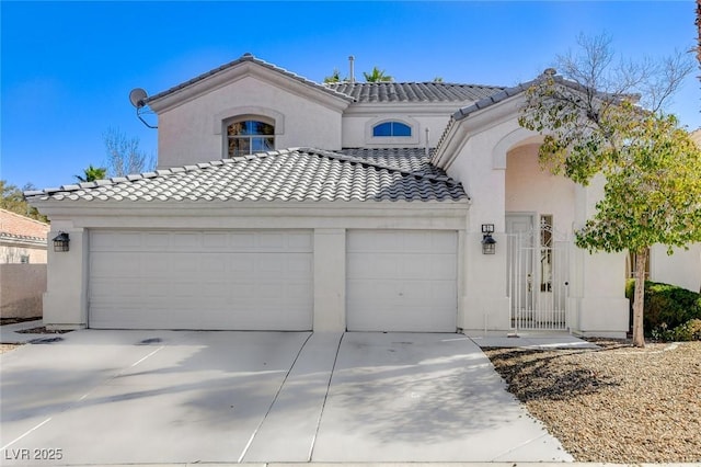 mediterranean / spanish home with a garage, a tile roof, and stucco siding