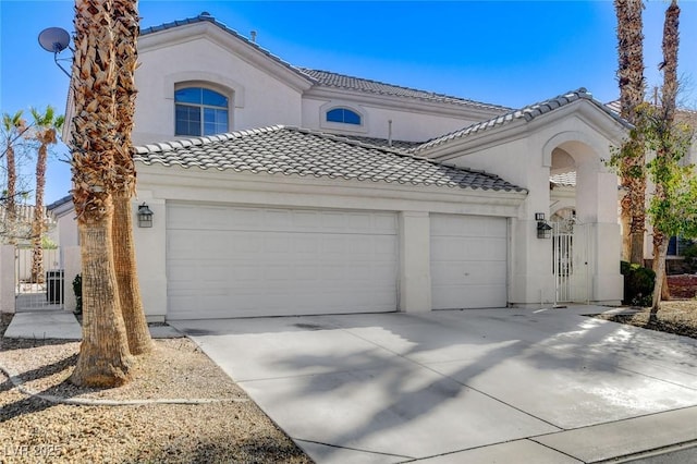 mediterranean / spanish-style house with an attached garage, driveway, a tile roof, and stucco siding