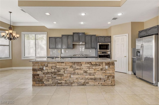 kitchen featuring decorative light fixtures, stainless steel appliances, visible vents, a sink, and an island with sink