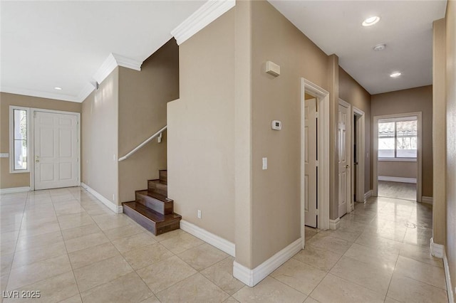 corridor featuring stairway, light tile patterned floors, baseboards, and ornamental molding