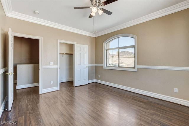 unfurnished bedroom featuring baseboards, dark wood finished floors, ceiling fan, crown molding, and a closet