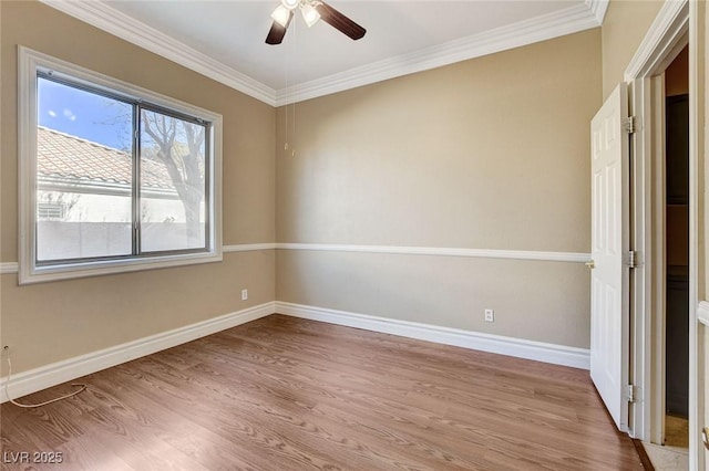 spare room featuring ornamental molding, light wood-type flooring, baseboards, and a ceiling fan