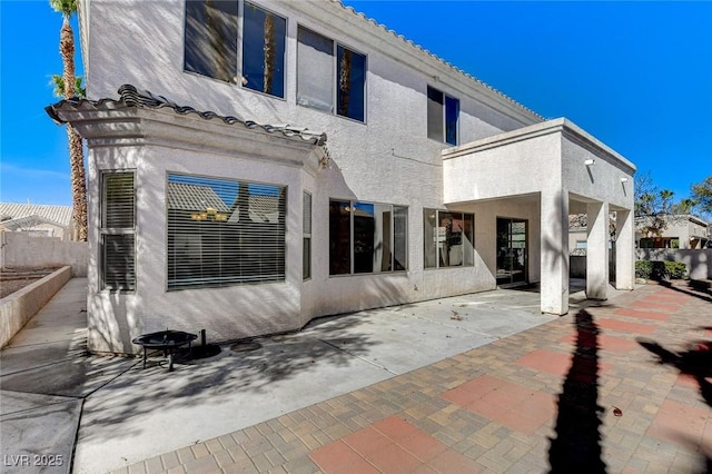 rear view of house with a patio area, fence, a tile roof, and stucco siding