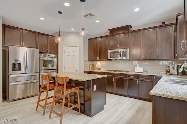 kitchen with a sink, visible vents, hanging light fixtures, appliances with stainless steel finishes, and a center island