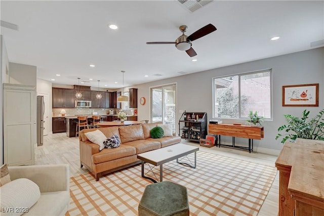 living area featuring light wood-style flooring, a ceiling fan, visible vents, and recessed lighting