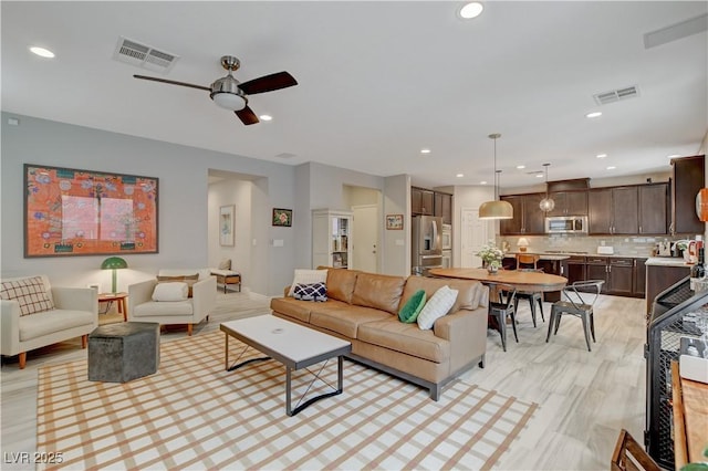 living area with ceiling fan, light wood-style floors, visible vents, and recessed lighting