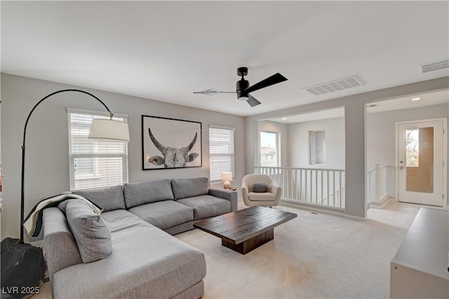 living area featuring plenty of natural light, visible vents, and light colored carpet