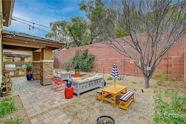 view of patio with an outdoor kitchen, a fenced backyard, and a grill