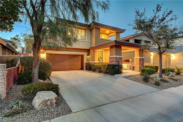 view of front of home with a garage, driveway, stone siding, and stucco siding