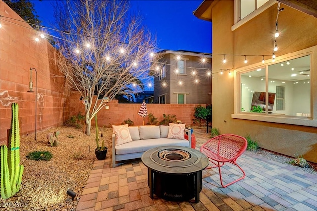 patio at twilight with an outdoor living space with a fire pit and a fenced backyard