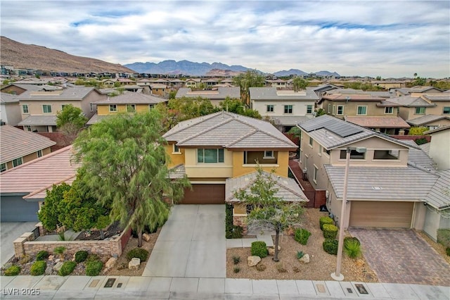 view of front facade featuring a residential view, an attached garage, decorative driveway, a mountain view, and stucco siding