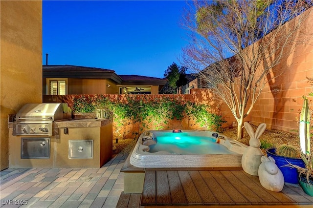 view of pool with a fenced backyard, hot tub deck surround, a grill, exterior kitchen, and a patio area