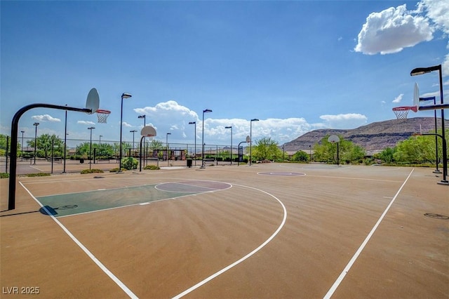 view of basketball court featuring community basketball court, a mountain view, and fence