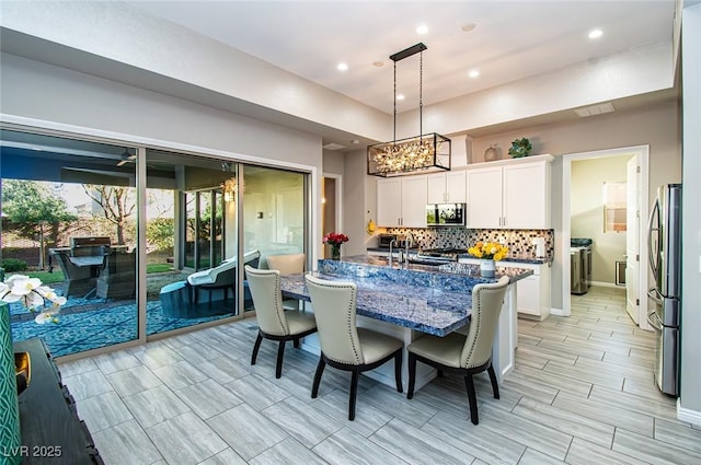 kitchen with a breakfast bar area, stainless steel appliances, white cabinets, backsplash, and dark stone counters