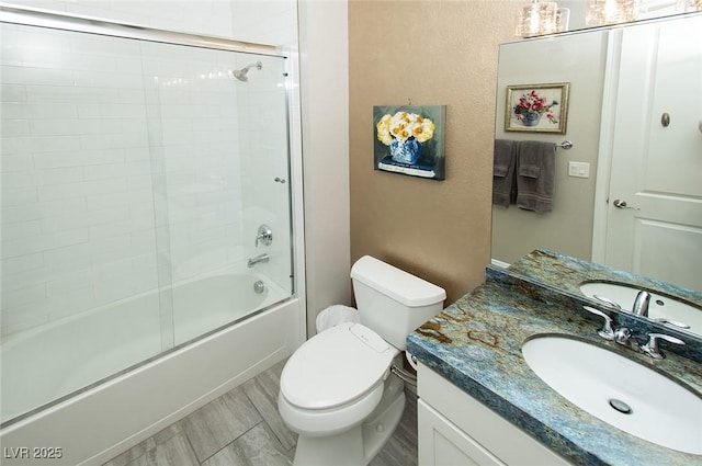 full bath with toilet, bath / shower combo with glass door, and vanity