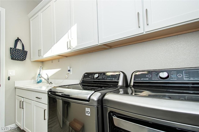 clothes washing area featuring washer and clothes dryer, a sink, and cabinet space