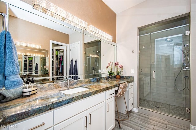 bathroom with a spacious closet, a stall shower, and vanity