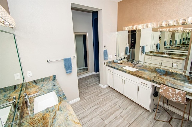 full bathroom featuring a sink, two vanities, and wood finish floors