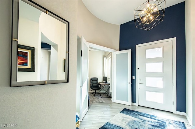 foyer featuring baseboards and a chandelier