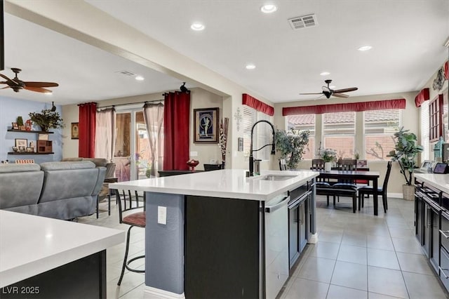 kitchen with a center island with sink, light countertops, visible vents, light tile patterned flooring, and a sink