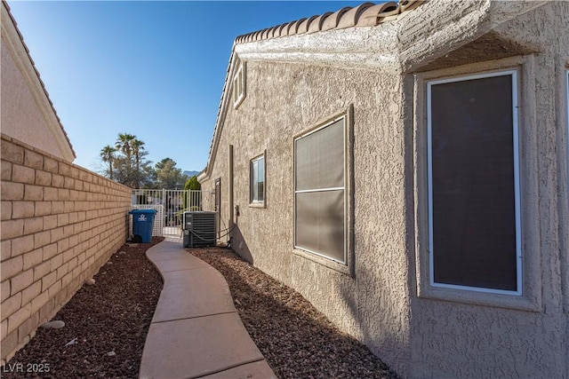 view of property exterior with fence, cooling unit, and stucco siding